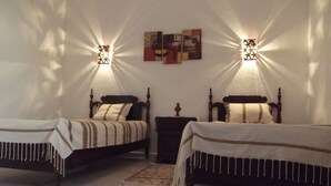 Een slaapkamer met twee houten bedden, een klein nachtkastje en twee wandlampen.