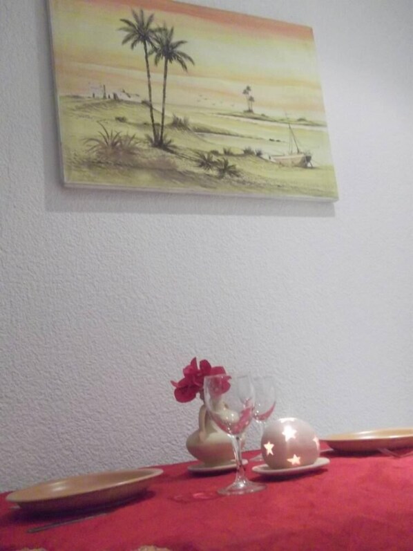 A dining table with a red tablecloth, a glass with a flower, and a plate with a star decoration.