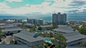 A coastal residential area with multiple two-story buildings, a large hotel with a swimming pool, and a view of the ocean. - Modern Ground Floor Condo w/ 2 Pools, Beach Access + Free Attraction Tickets! (Santa Rosa Beach)