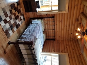 Cozy cabin with a bunk bed for two, a small table, and a window with a view.