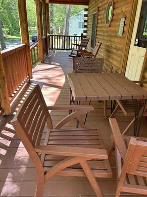 Une terrasse en bois avec une table de pique-nique et des bancs, entourée d’une balustrade en bois.
