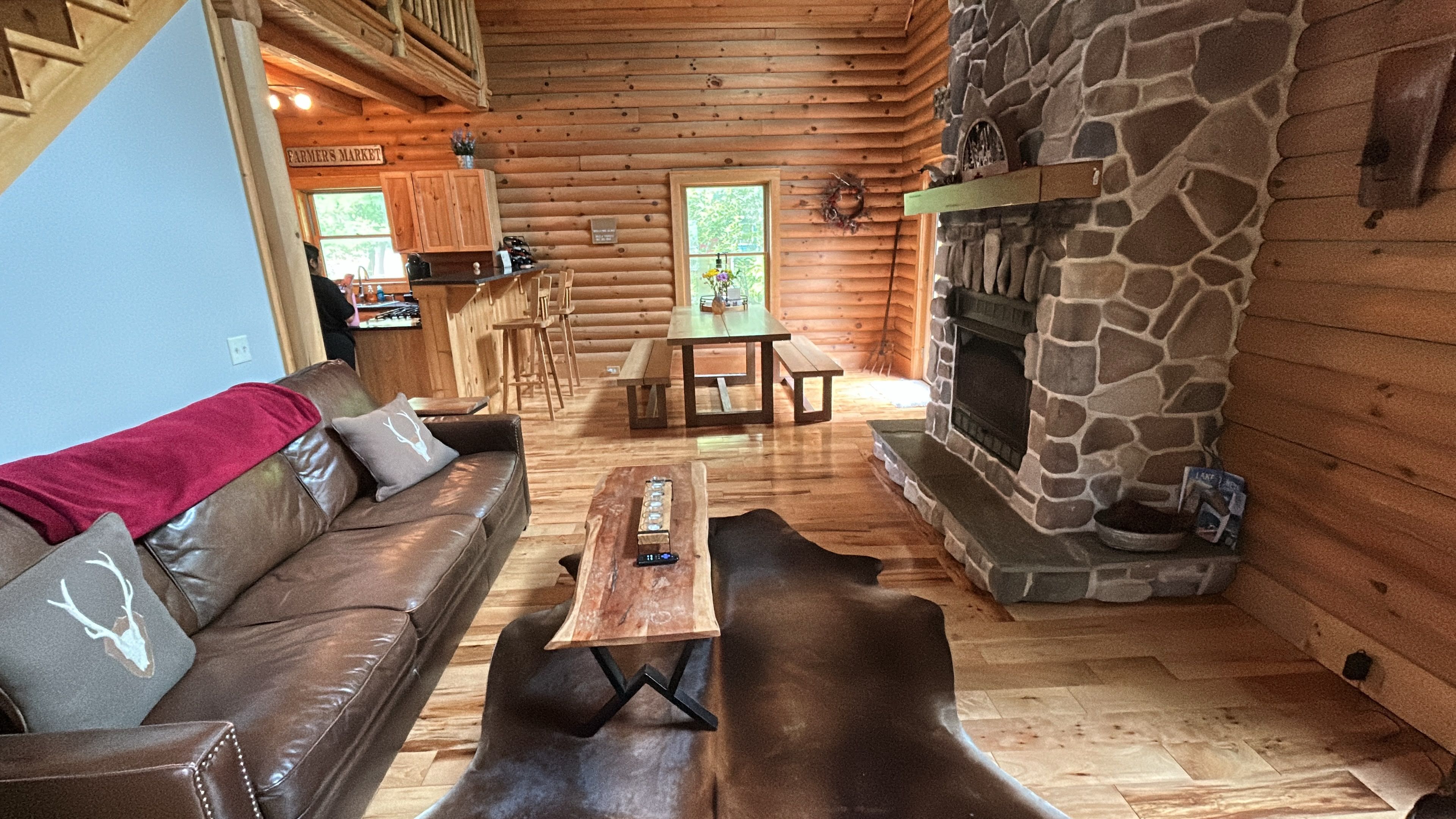 L’intérieur d’une cabane en rondins, avec une cheminée en pierre, des meubles en bois et un canapé en cuir.