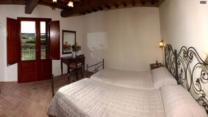 Quarto com duas camas, uma escrivaninha e vista para o exterior.