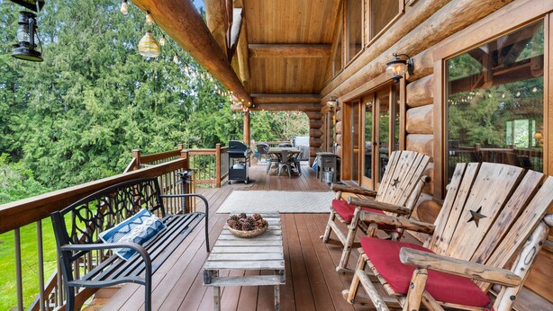 Una terraza de madera con un banco, sillas y una mesa.