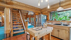 Una cocina rústica con vigas de madera, un refrigerador de acero inoxidable y una mesa de madera con taburetes de bar.