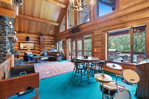 A log cabin interior with a drum set, a fireplace, and a stone wall. - A Log House in a Private Forest with Hot Tub! (Ridgefield)