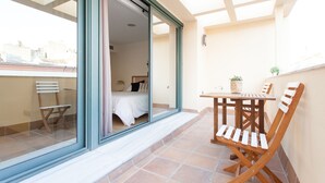 A balcony with a bed, a table, and chairs. - Albareda 5 - One Bedroom Apartment, Sleeps 4 (Sevilla)