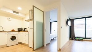 A modern apartment with a kitchen, a washing machine, a microwave, and a bed in the adjacent room. - Albareda 5 - One Bedroom Apartment, Sleeps 4 (Sevilla)
