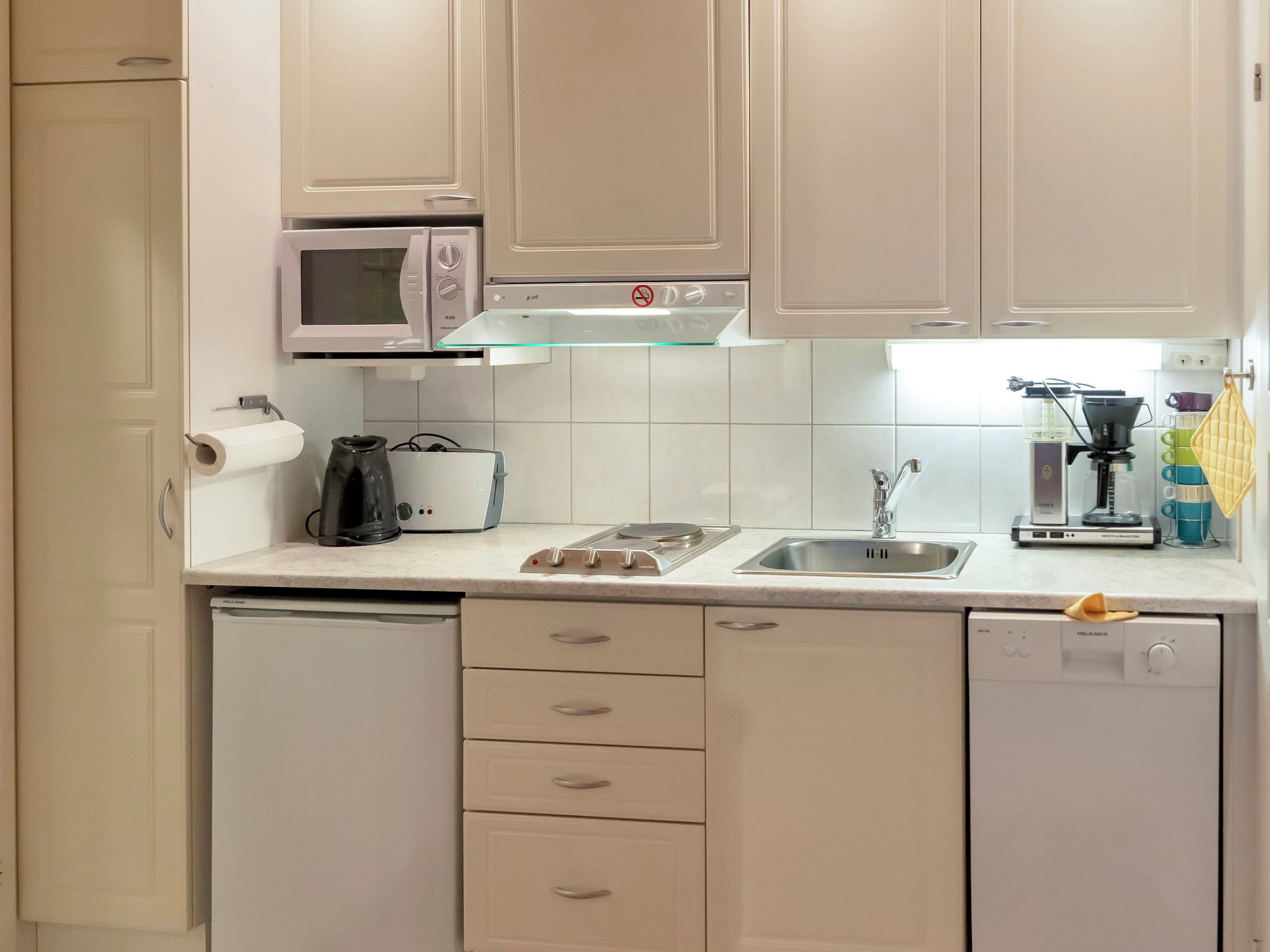Une cuisine moderne avec des meubles blancs, un four à micro-ondes, une machine à café et un lave-vaisselle.