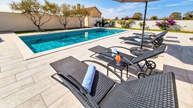 A swimming pool with lounge chairs and an umbrella. - Vacation home Anić by Interhome (Novigrad (Zadar))