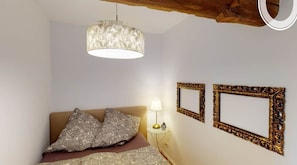 Quarto com cama, luminária de cabeceira e dois espelhos de parede elaborados.