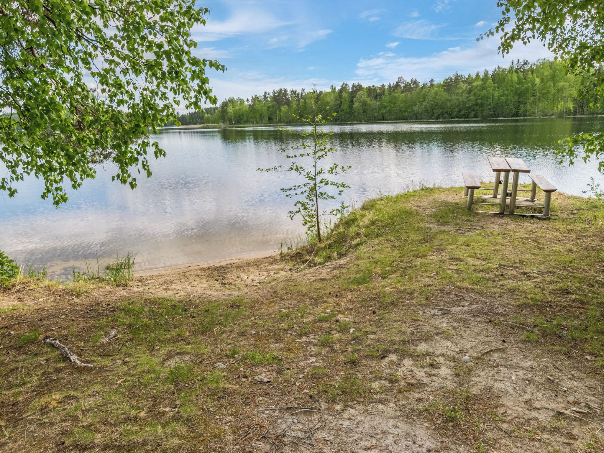 En picknickplats vid sjön med en bänk och ett bord.