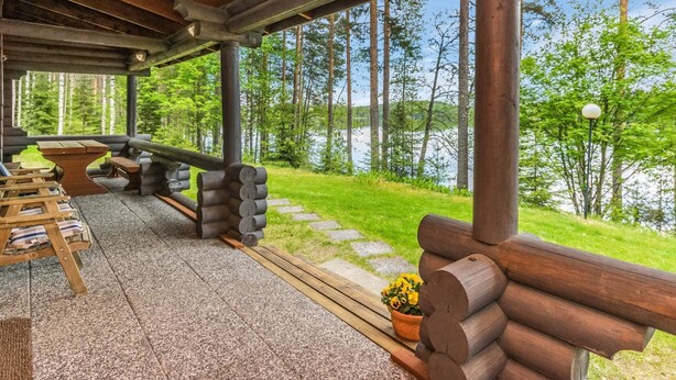 Een overdekt terras met uitzicht op een meer en bos.