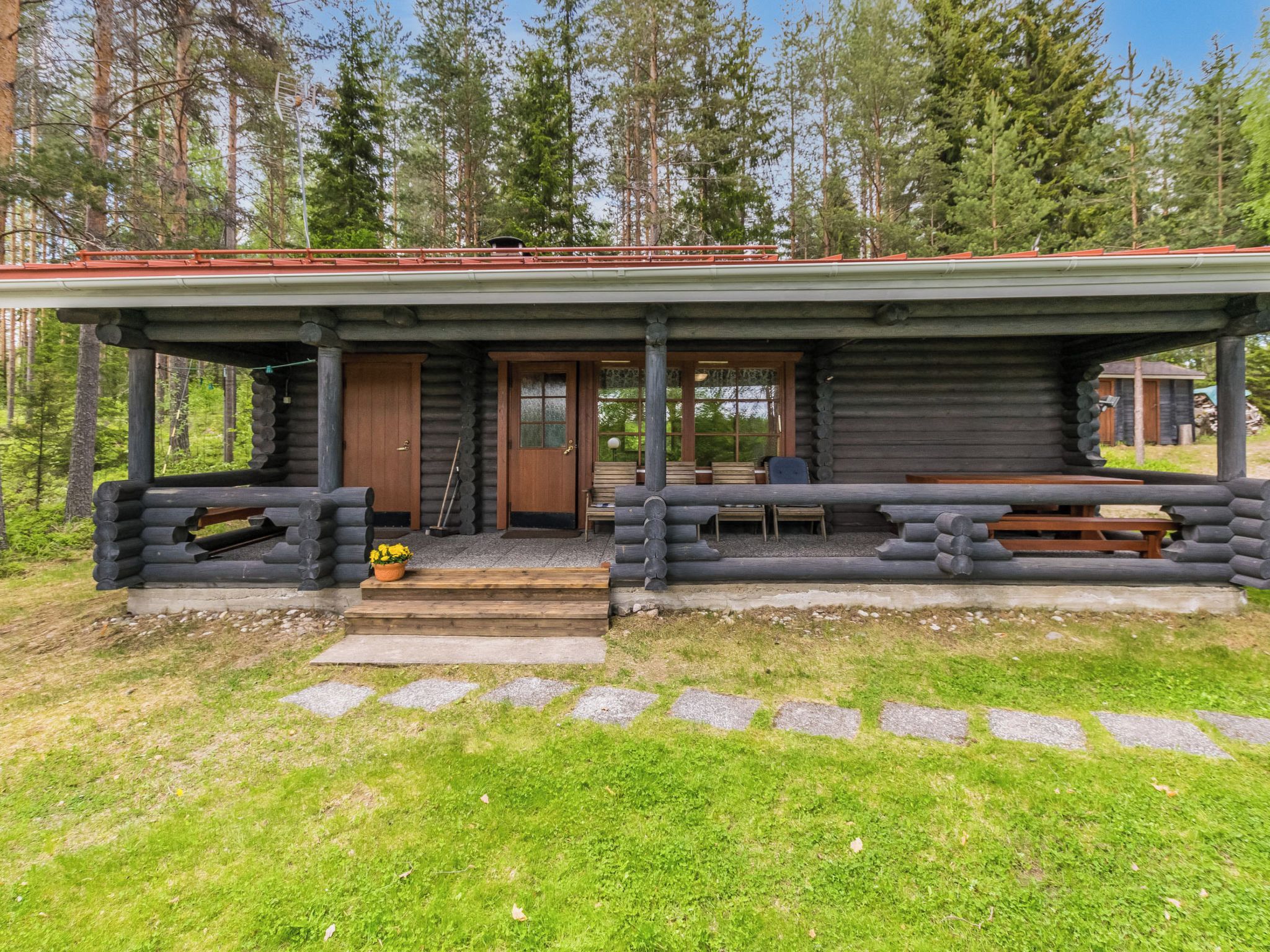 A log cabin with a porch, a door, and a bench.