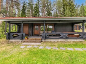 A log cabin with a porch, a door, and a bench.