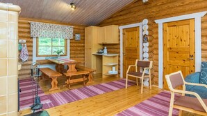 Een gezellig houten interieur met een eettafel, stoelen, een keuken en een groot raam.