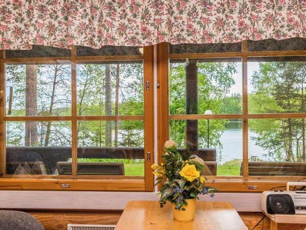 A room with large windows, a wooden table, and a floral curtain.
