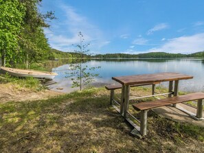 A lakeside picnic area with a bench and a boat. - Lohi, cjoe237 a by Interhome (Heinävesi)