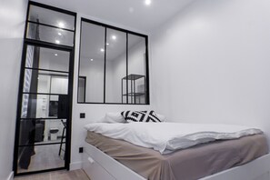 A modern bedroom with a bed, a large mirror, and a wardrobe. - Aboukir Design Flat 1 (Paris)