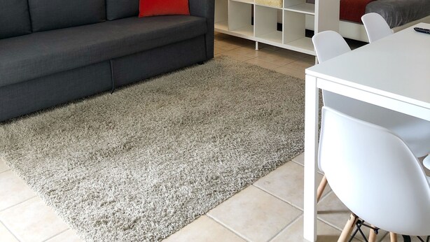 A modern living room with a grey sofa, a white coffee table, and a white shelving unit. - Boulevard Park IV 104 - This is Puerto Rico (Mayagüez Pueblo)