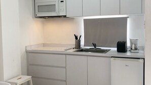 A compact kitchen with white cabinets, a microwave, a coffee maker, and a small refrigerator. - Boulevard Park IV 104 - This is Puerto Rico (Mayagüez Pueblo)