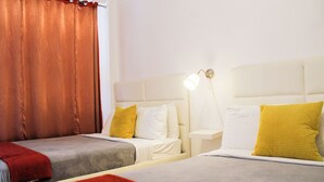 A hotel room with two beds, a nightstand, a lamp, and a window with curtains. - Boulevard Park IV 104 - This is Puerto Rico (Mayagüez Pueblo)