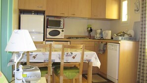 A compact kitchen with wooden cabinets, a microwave, a coffee maker, and a dishwasher. - wooden chalet in the gardens of St Pierre (Saint-Pierre-D'oléron)