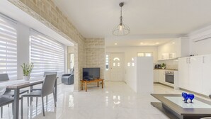 A modern living room with a TV, dining area, kitchen, and a stone wall. - Chavicoto by Interhome (Empuriabrava)