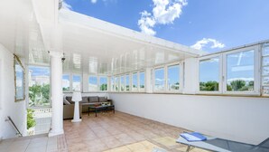 A spacious patio with a sun lounger, a seating area with a sofa and table, and large windows offering a view of the surrounding area. - Chavicoto by Interhome (Empuriabrava)