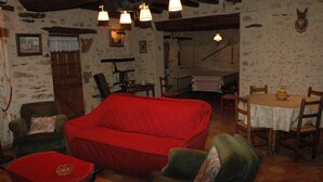A rustic room with a red sofa, wooden chairs, a small table, and a dining table with chairs.
