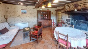 A rustic room with a stone wall, wooden furniture, a fireplace, and a tiled floor.