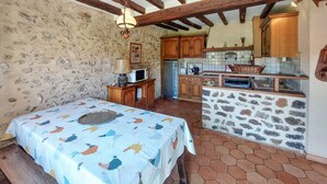 A rustic kitchen with stone walls, wooden cabinets, and a tiled backsplash.