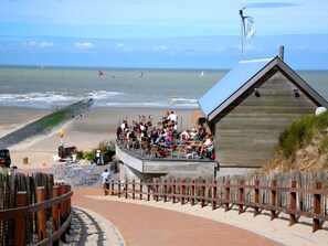A wooden building with a sloped roof overlooking a beach.
