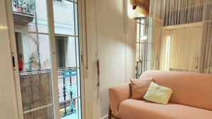 Un salon comprenant un canapé, une petite table et une vue sur un balcon extérieur, accessible par une porte coulissante.