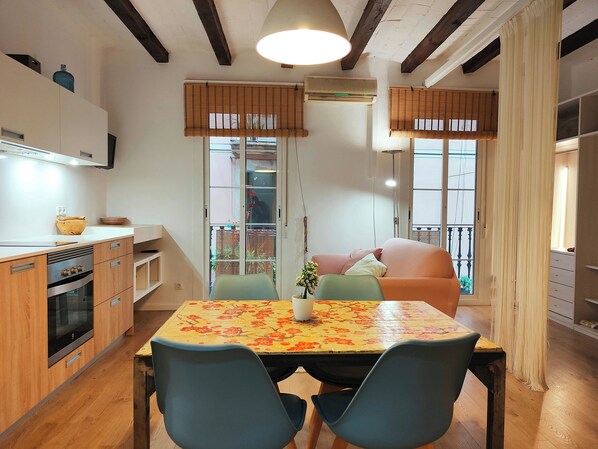 A modern kitchen with wooden cabinets, a built-in oven, and a dining area with a table and chairs.