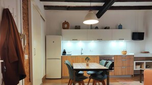 Une cuisine moderne avec des meubles en bois, une table à manger avec des chaises et un luminaire suspendu.