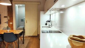Une cuisine moderne avec un plan de travail blanc, un évier en acier inoxydable et un saladier en bois posé sur le plan de travail.
