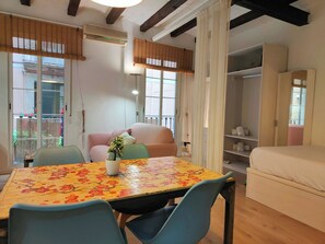 A room with a dining table, chairs, a sofa, a bed, and a wardrobe.