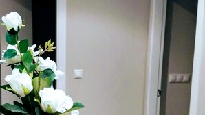 A hallway with a white vase containing white flowers on a white table. - Housing with sea views. (Sanxenxo)