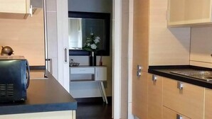 A modern kitchen with wooden cabinets, a black countertop, and a small dining area with a table and chairs. - Housing with sea views. (Sanxenxo)