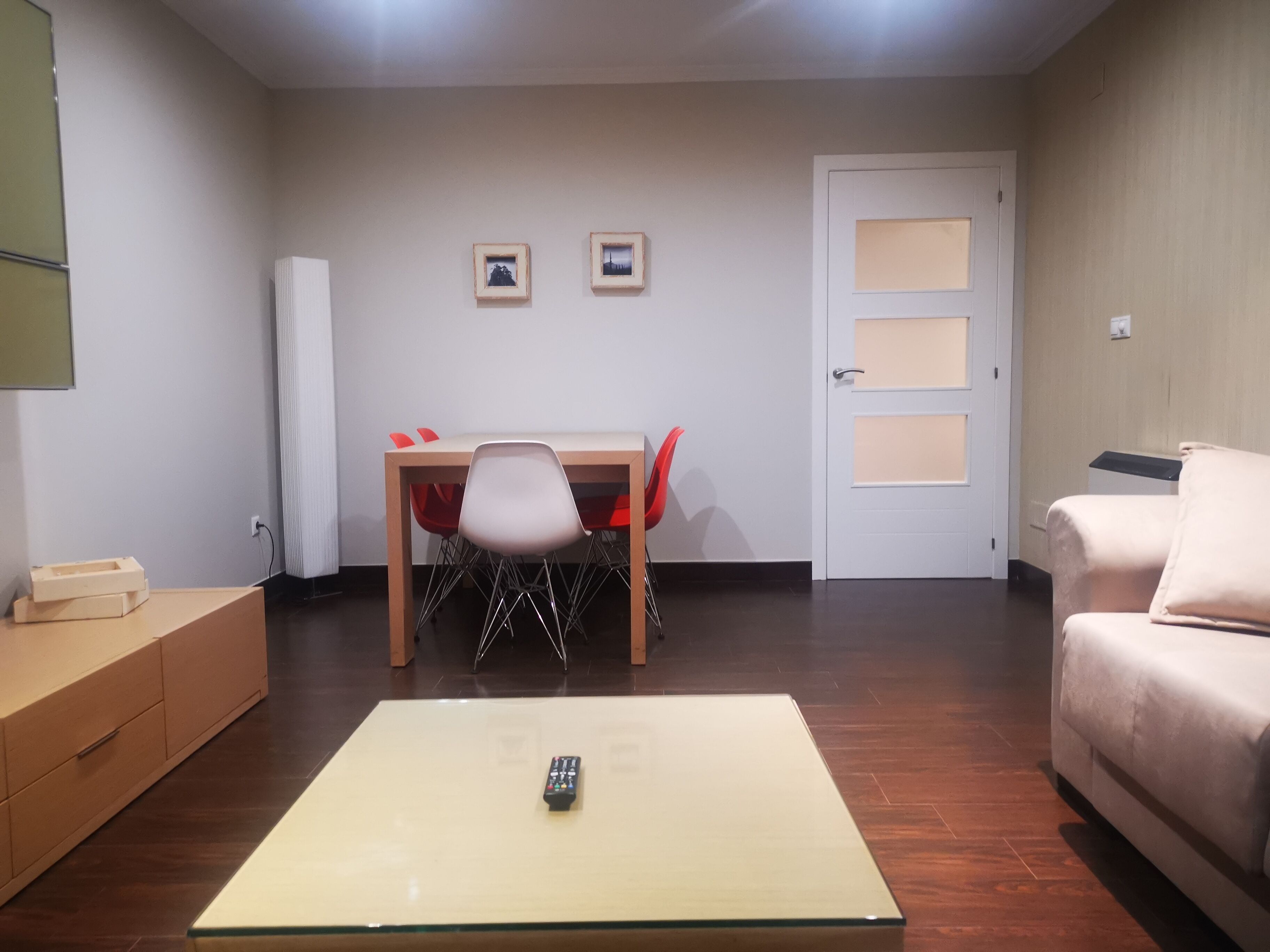 A compact living space with a dining table, a single chair, a sofa, and a glass coffee table.