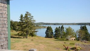Une vue sur le lac, avec un bâtiment en bois, une table de pique-nique et un banc.