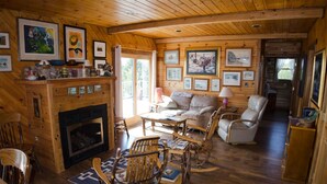 Un intérieur de chalet chaleureux avec une cheminée, des murs en bois et des tableaux encadrés.