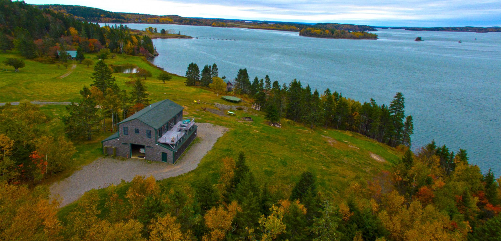 A large, rustic building with a green roof, surrounded by a lush landscape and a lake.