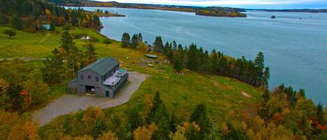 A large, rustic building with a green roof, surrounded by a lush landscape and a lake.