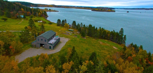 A large, rustic building with a green roof, surrounded by a lush landscape and a lake. - On the top of ledge overlooking Cobscook Bay (Eastport)
