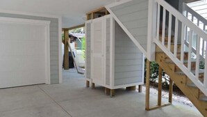 A spacious interior with a concrete floor, a wooden staircase, and a white door leading to a garage. - Barefoot 'N Salty - Walk to Beach in Surfside Beach (Surfside Beach)