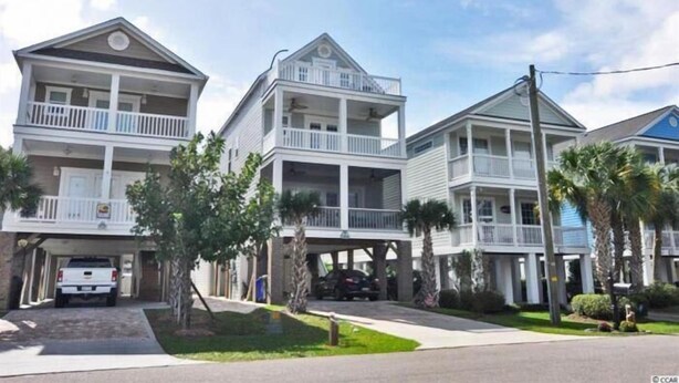 A row of three-story beachfront condominiums with balconies, a covered parking area, and palm trees. - Barefoot 'N Salty - Walk to Beach in Surfside Beach (Surfside Beach)