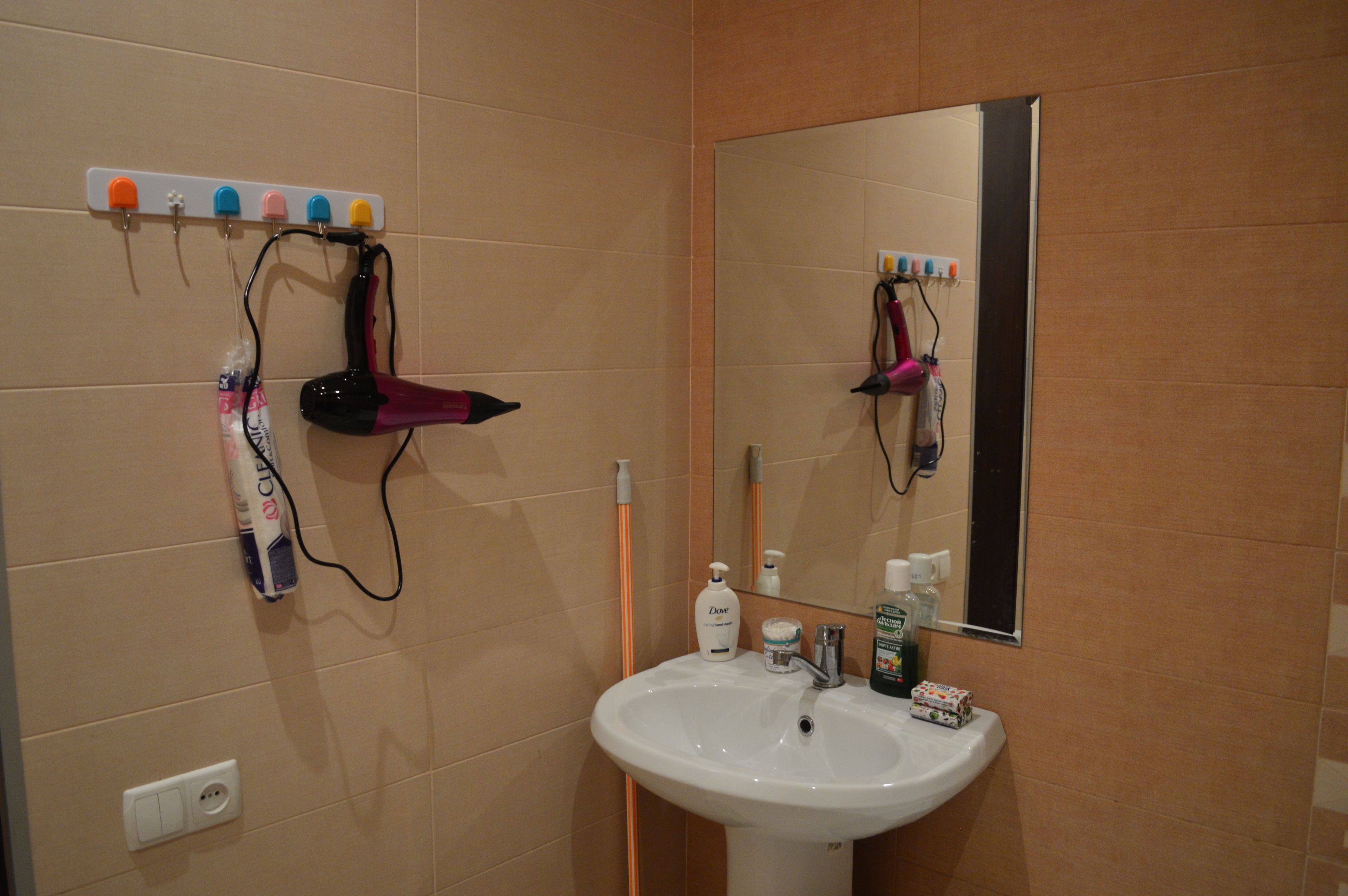 Un bagno con lavandino, specchio e asciugacapelli su un supporto a parete.
