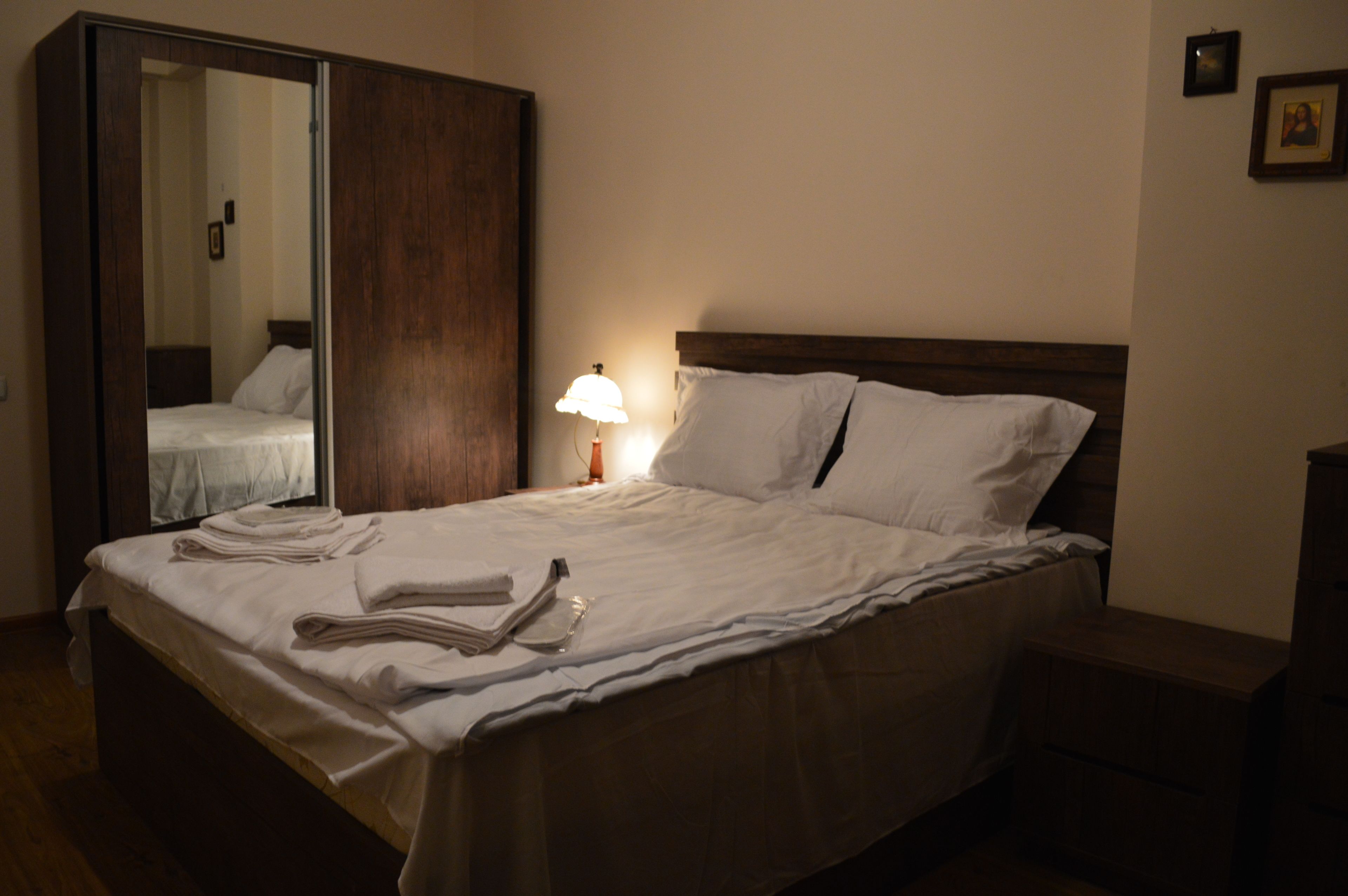 Una cama bien hecha con sábanas blancas y una lámpara al lado.